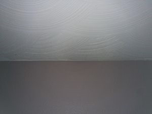 Photo of swirl drywall texture on the ceiling and orange peel texture on the wall